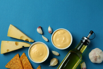 Cheese sauce, ingredients and chips on blue background