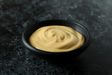 Bowl with cheese sauce on black smokey background