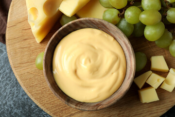 Board with cheese sauce, grape and cheese on black smokey table with kitchen towel