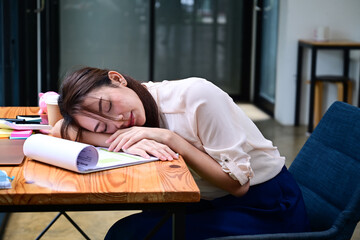 Obraz premium Overworked female office worker sleeping at her office desk.
