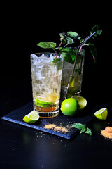 two colorful summer  mojito cocktails with mint, lime and ice cubes on a black background