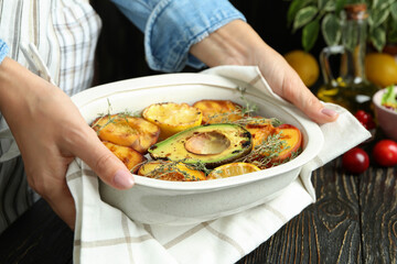 Woman in apron holds dish with grilled peach, close up