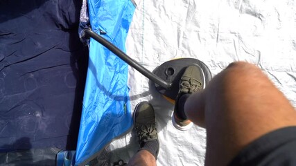 Man pumping air mattress with foot pump to prepare sleeping in tent, above view