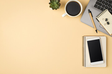 Overhead photo of laptop notebook pen paperclips smartphone plant and cup of coffee isolated on the...