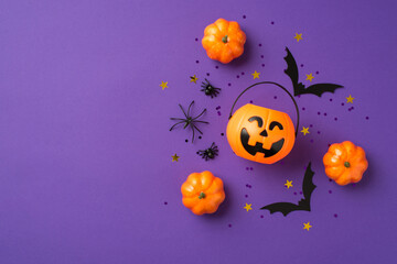 Top view photo of halloween decorations pumpkins basket spiders black sequins golden stars bat silhouettes on isolated violet background with copyspace