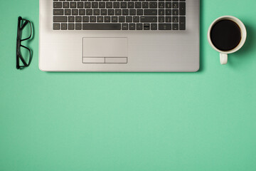 Top view photo of grey laptop keyboard glasses and cup of coffee on isolated turquoise background with copyspace
