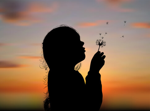 irl blowing on dandelion at sunset