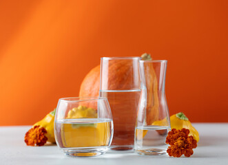 Autumn still life of pumpkins distorted through water in glasses. The concept of Thanksgiving or...