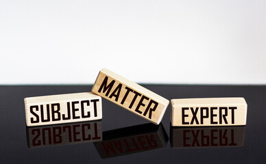 text SUBJECT MATTER EXPERT on wooden blocks and black and white background.