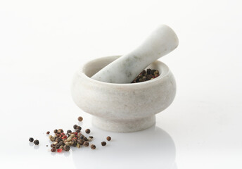 Marble mortar and pestle with spices for grinding isolated on white.