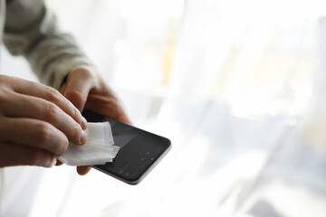 Сleaning concept. Wipe dirt off surfaces. Disinfectant treatment of phone screenl. Sanitary treatment at home quarantine.