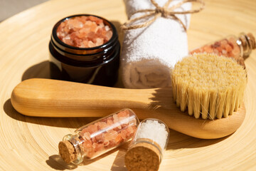 Spa treatment personal accessories with face pbush, pink aromatic salt and rolled white towel. Skin care riutine