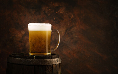 glass of beer on an old oak barrel, iron rings, dark background.