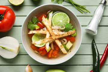 Composition with tasty Sopa de Lima soup on color wooden background