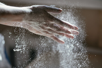 Fototapeta premium Glowing particles of flour in the air and a woman's hand close-up, photo of a hand in motion, blurred background