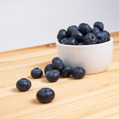 Fresh blueberry in white dish on wooden background