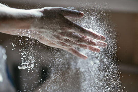 Glowing particles of flour in the air and a woman's hand close-up, photo of a hand in motion, blurred background