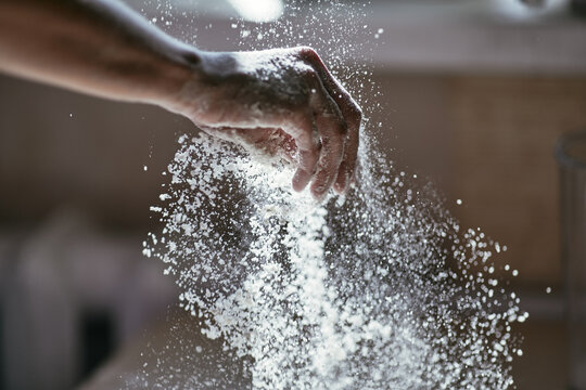 Glowing particles of flour in the air and a woman's hand close-up, photo of a hand in motion, blurred background