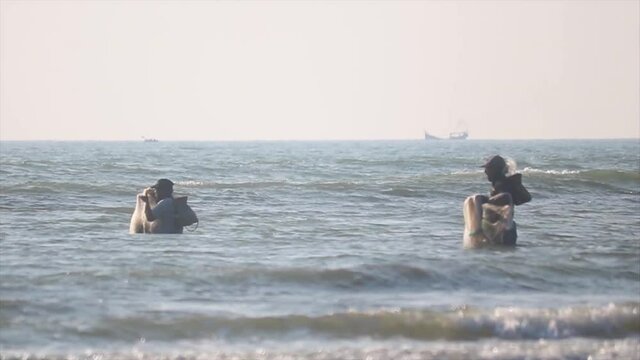 Two men fishing in the water at the shoreline with nets.