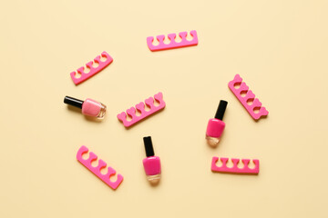 Bottles of nail polishes and toe dividers on color background