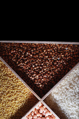 A set of grain cereals. Rice, buckwheat and millet groats in a wooden tray. A grocery set of cereals. Import of grain.