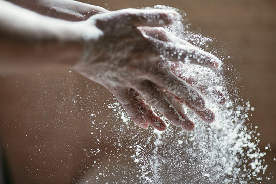 Girl shaking off flour in palms, close-up photo of hands