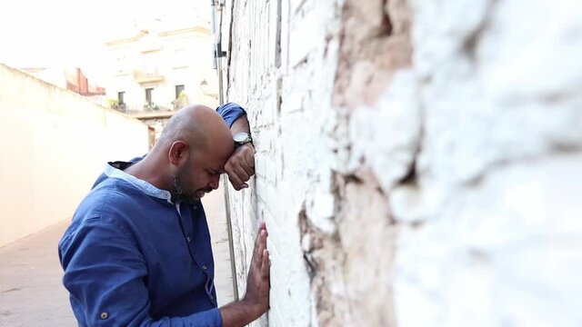 Sad male depressed, expressing anger and despair on a wall