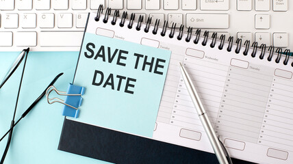 SAVE THE DATE text on blue sticker on planning and keyboard,blue background