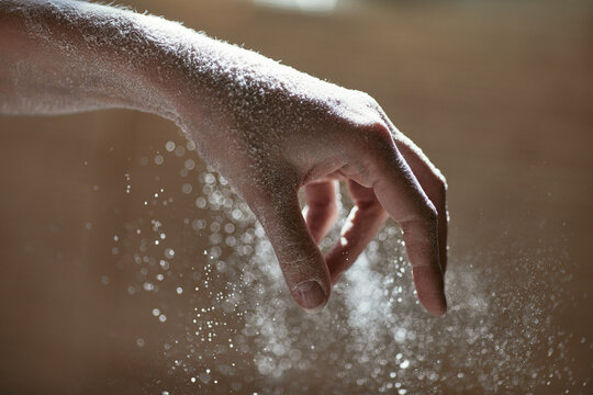 Girl scattering flour, close-up photo of her hand with grains of flour, horizontal background with the cooking process