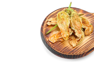 Board with fried zucchini flowers on white background