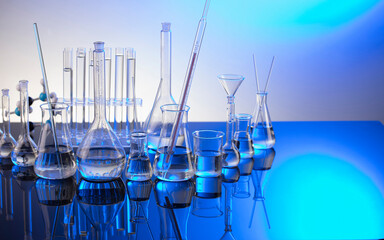 Laboratory investigations. Glass tubes and beakers on blue background.