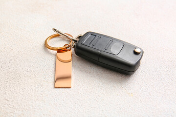 Car key with stylish keychain on light background, closeup
