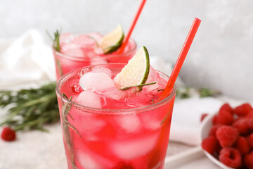 Glasses of tasty raspberry lemonade and berries on light background, closeup