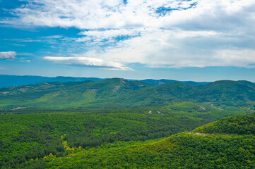 Crimean mountains covered with green forest against a blue sky with white clouds