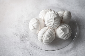 White marshmallow lies on a transparent plate. View from above