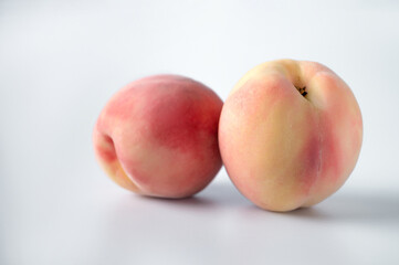 Fototapeta na wymiar Two peach fruits lie on a white isolated background