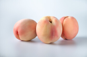 Fototapeta na wymiar Three peach fruits lie on a white isolated background.