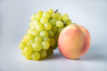 Bunch of green grapes and one pink peach isolated on white