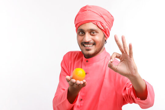 Indian farmer holding an orange fruit in hand over white background.