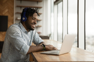 African guy wear wireless headphones using laptop smile enjoy remote conversation on video...