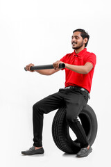 Handsome young male mechanic with new tires isolated on white background.
