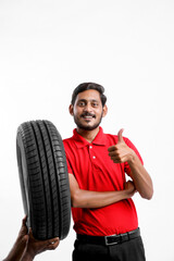 Handsome young male mechanic with new tires isolated on white background.