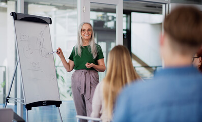 Obraz premium University students with teacher studying indoors, lesson and presentation concept.