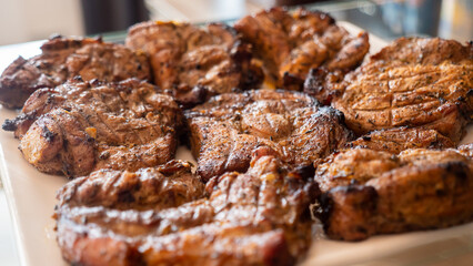Well-fried steaks lie on a plate and wait for their turn