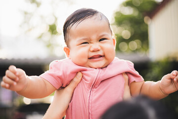 Asian mother raises her daughter lift up in the sky. mother holding daughter in arms. Happy asian family child and mom walking outdoor nature. Happy mother's Day