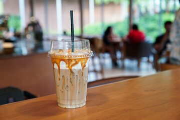 Iced caramel coffee. A cup of coffee mixed with milk and caramel syrup on wooden table at coffee cafe.