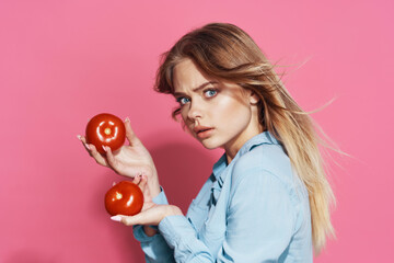 woman in blue shirt holding tomatoes fun food pink background