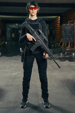 Serene military woman with a firearm looking ahead