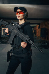 Fototapeta na wymiar Woman with a firearm standing at an indoor shooting range