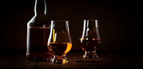 Scotch Whiskey in special glasses and bottle, old wooden background with negative space